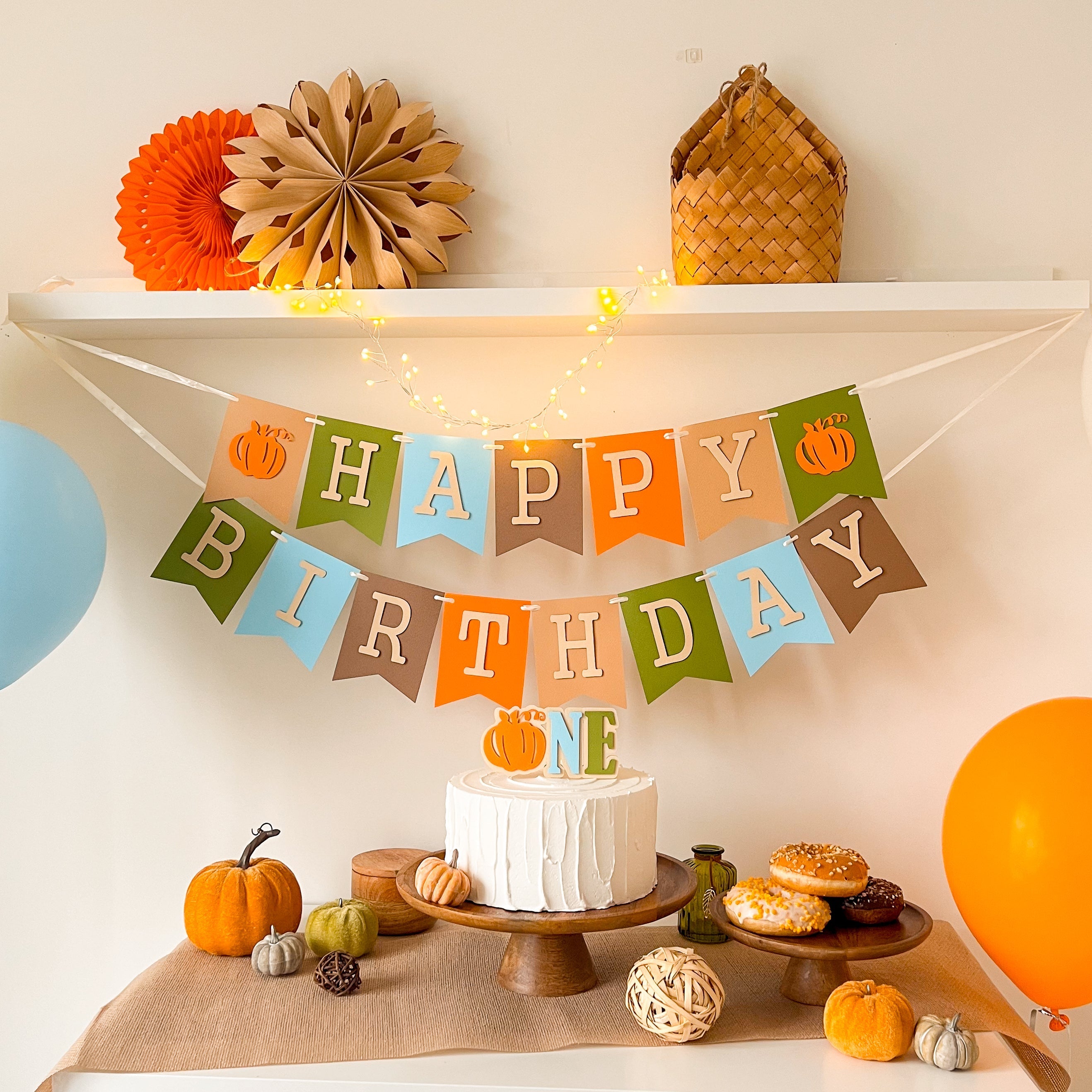 Fall-themed high chair banner with pumpkins for baby’s first birthday.