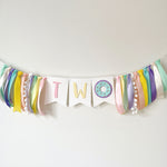 A pastel birthday banner spelling 'TWO' with a donut decoration