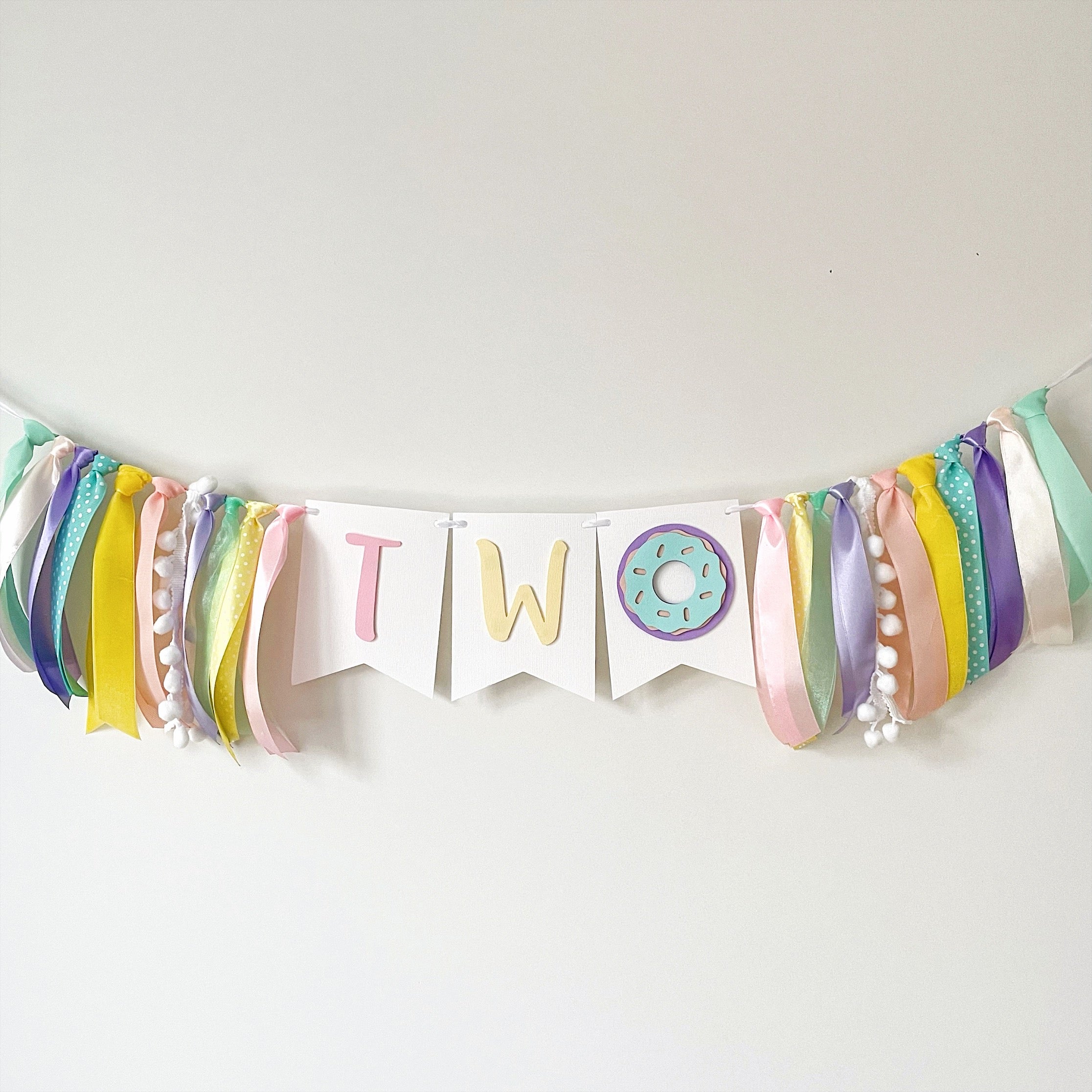 A pastel birthday banner spelling 'TWO' with a donut decoration