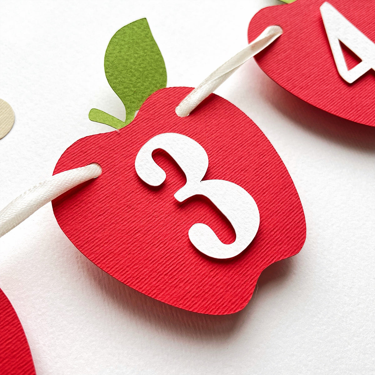 Close-up of red apple 12 month photo banner cards with white numbers for a first birthday milestone display.