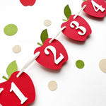 Apple monthly photo banner hanging on twine, showing red apple cutouts with numbers 2, 3, and 4.
