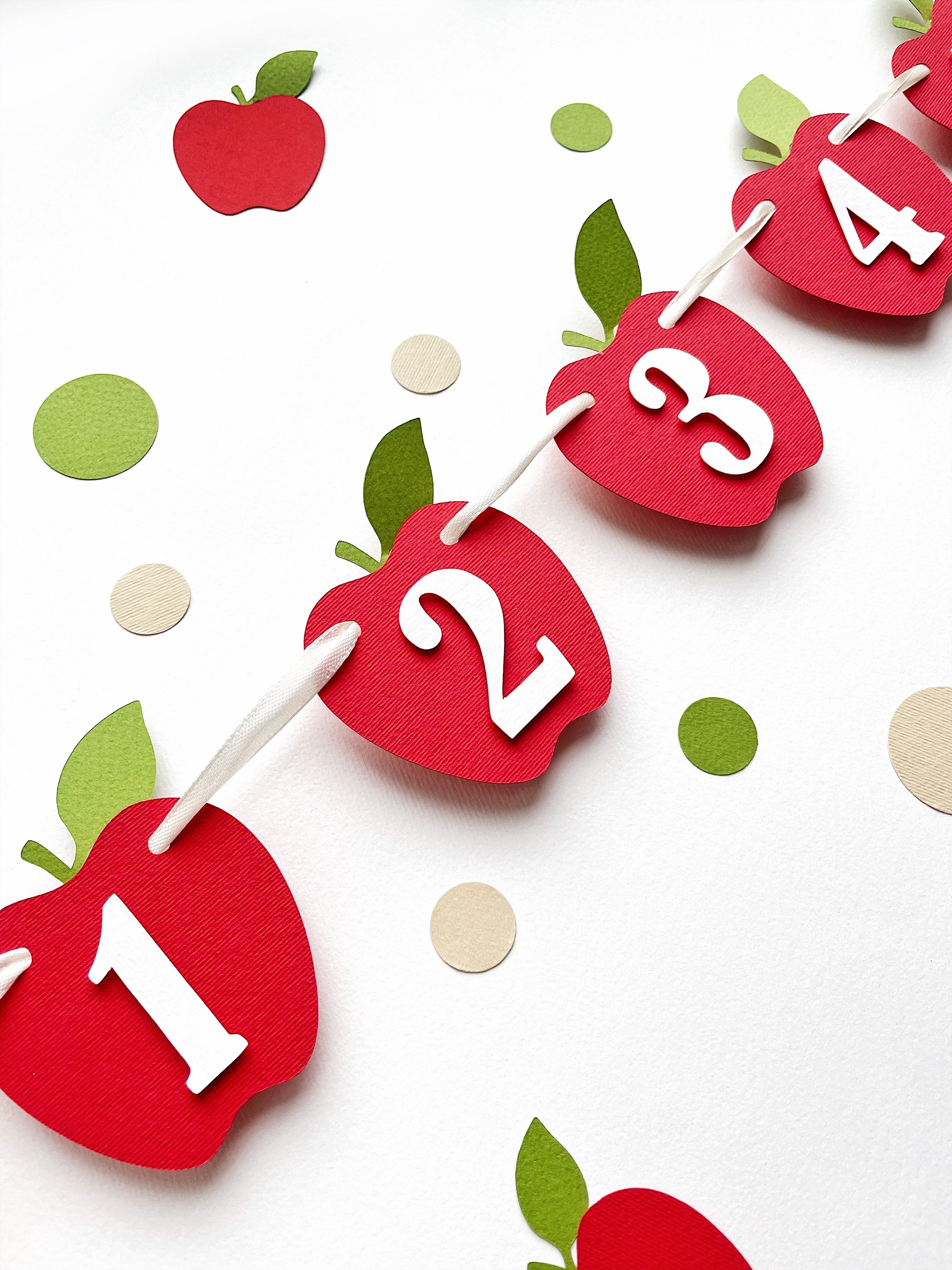 Apple monthly photo banner hanging on twine, showing red apple cutouts with numbers 2, 3, and 4.