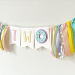 A pastel birthday banner spelling 'TWO' with a donut decoration