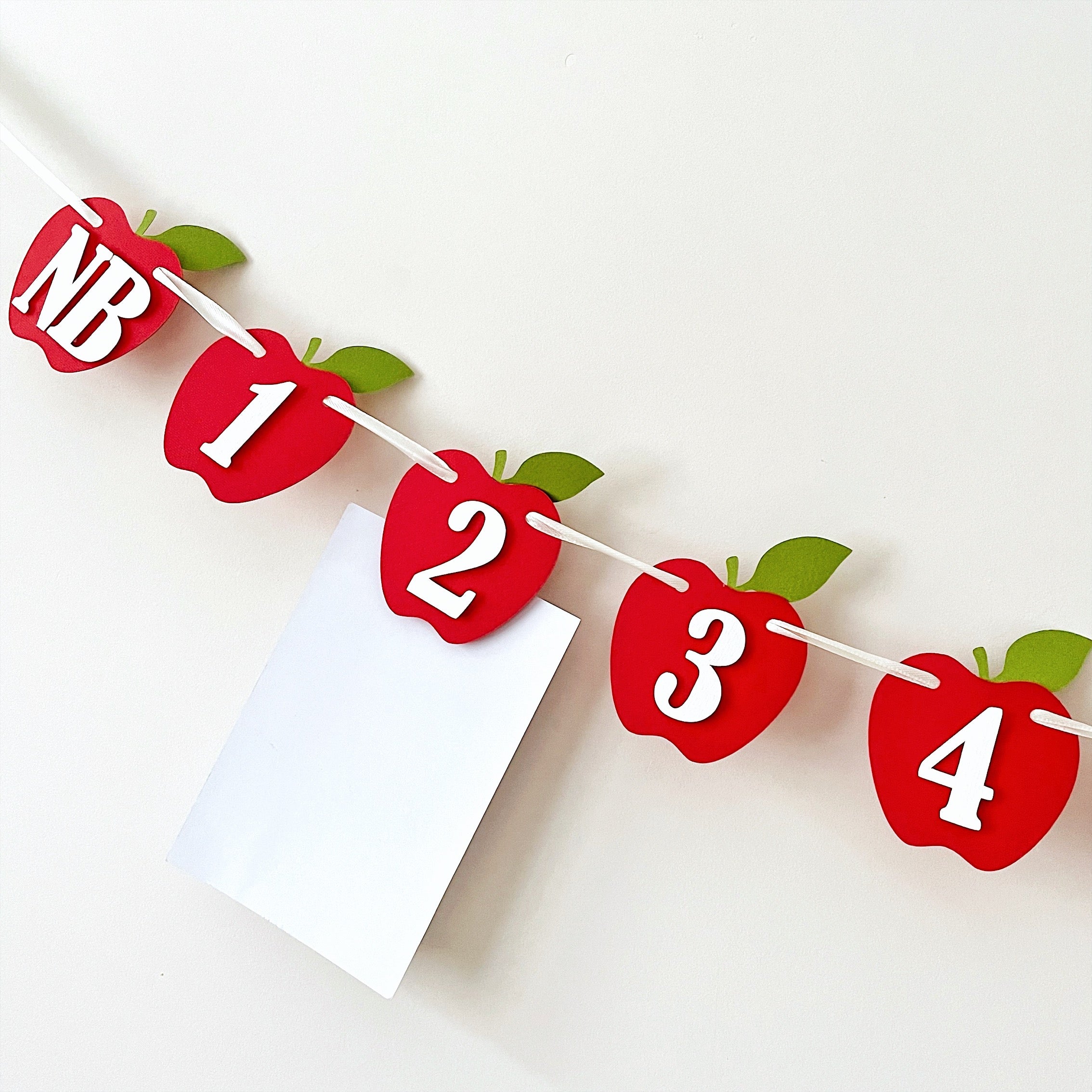 Apple 12 month photo banner displayed with a photo card template attached for a 1st birthday party setup.