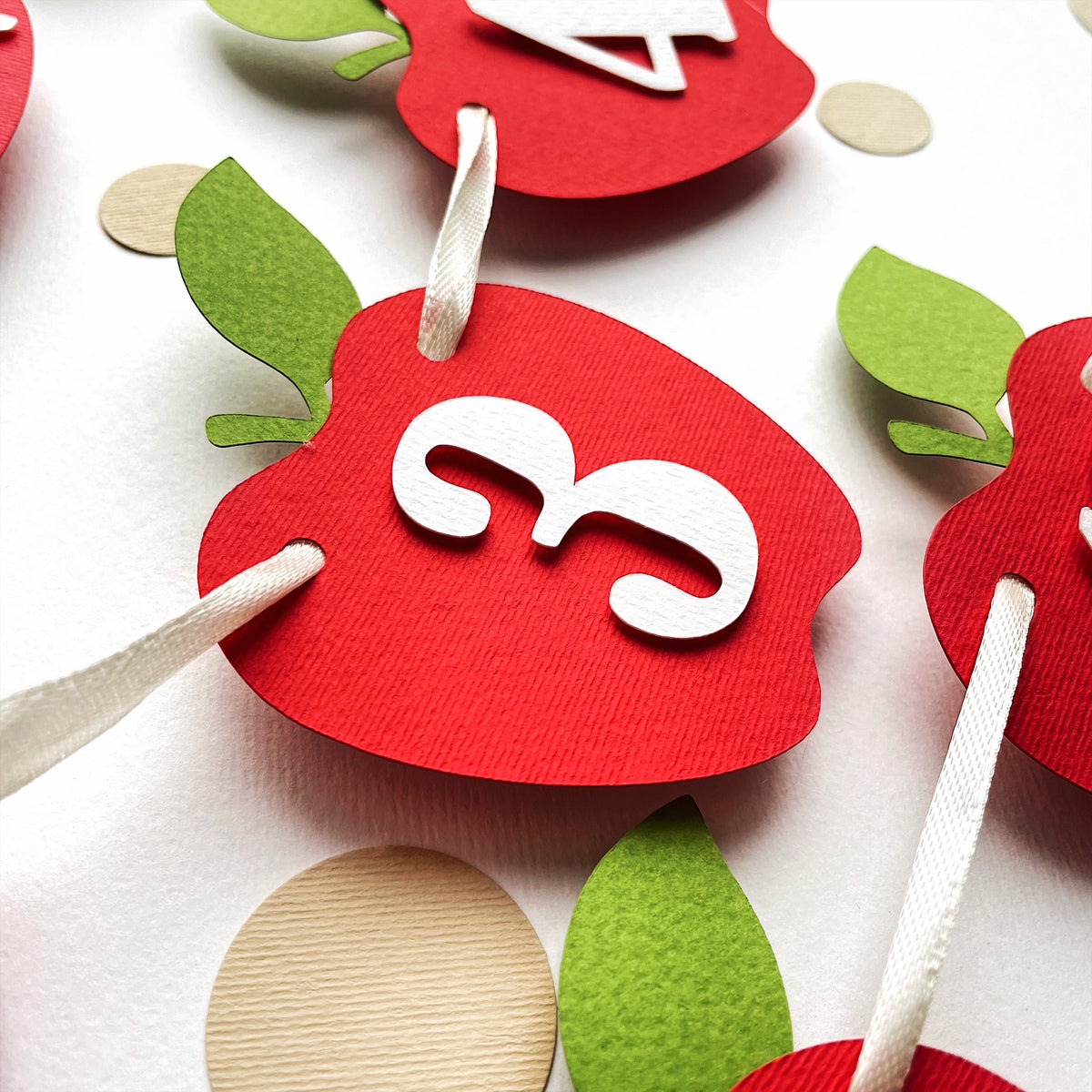 Detailed close-up showing the multi-layered red cardstock apple cutouts and ribbon details.