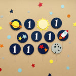 Space-themed 1st birthday cupcake toppers featuring a rocket ship, celestial stars, and solar system designs for a boy's first trip around the sun party.