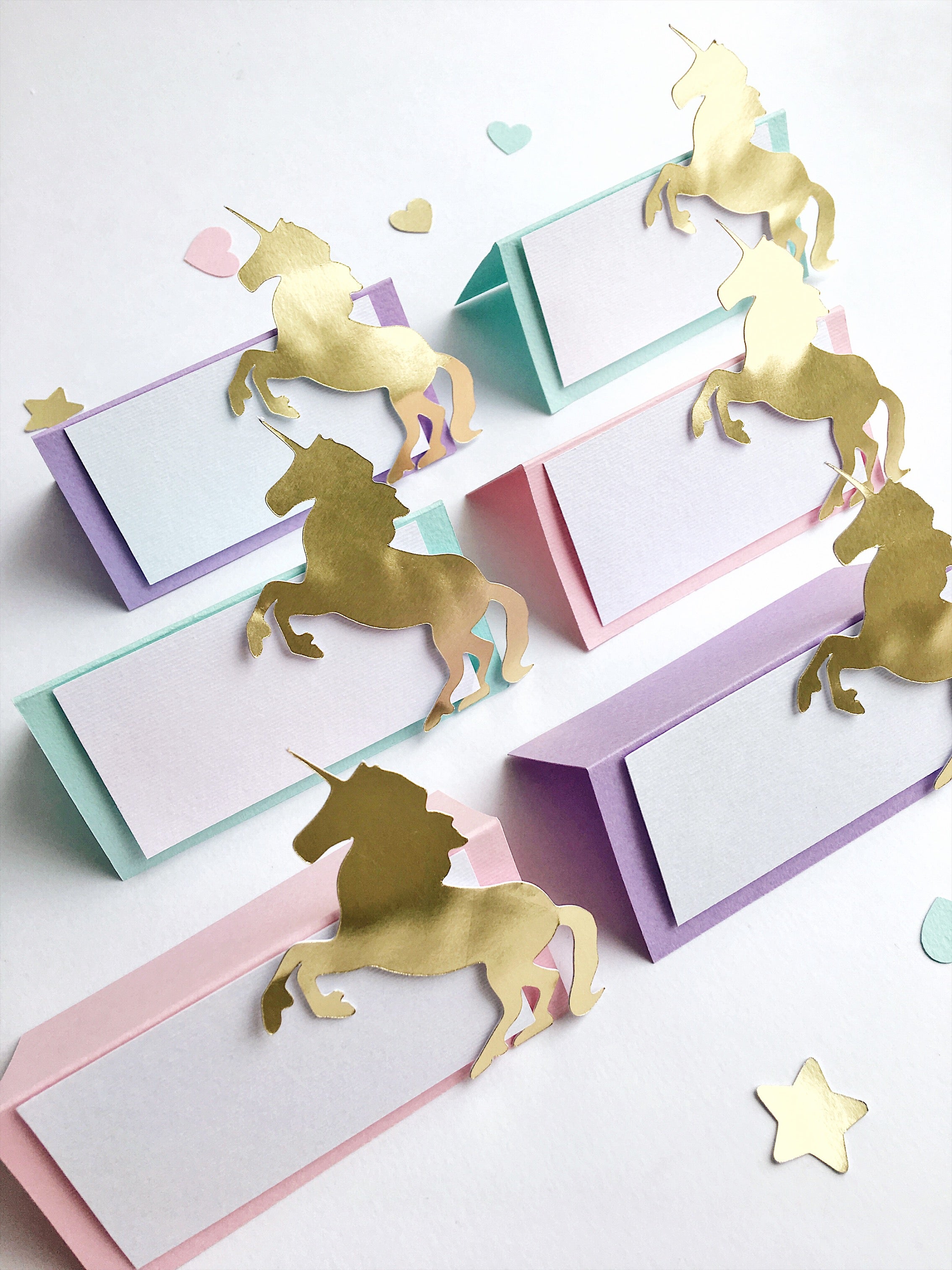 Gold unicorn decorations on colorful place cards with a white background