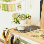 Hand holding a tractor cupcake topper to show size suitable for standard muffins and cupcakes