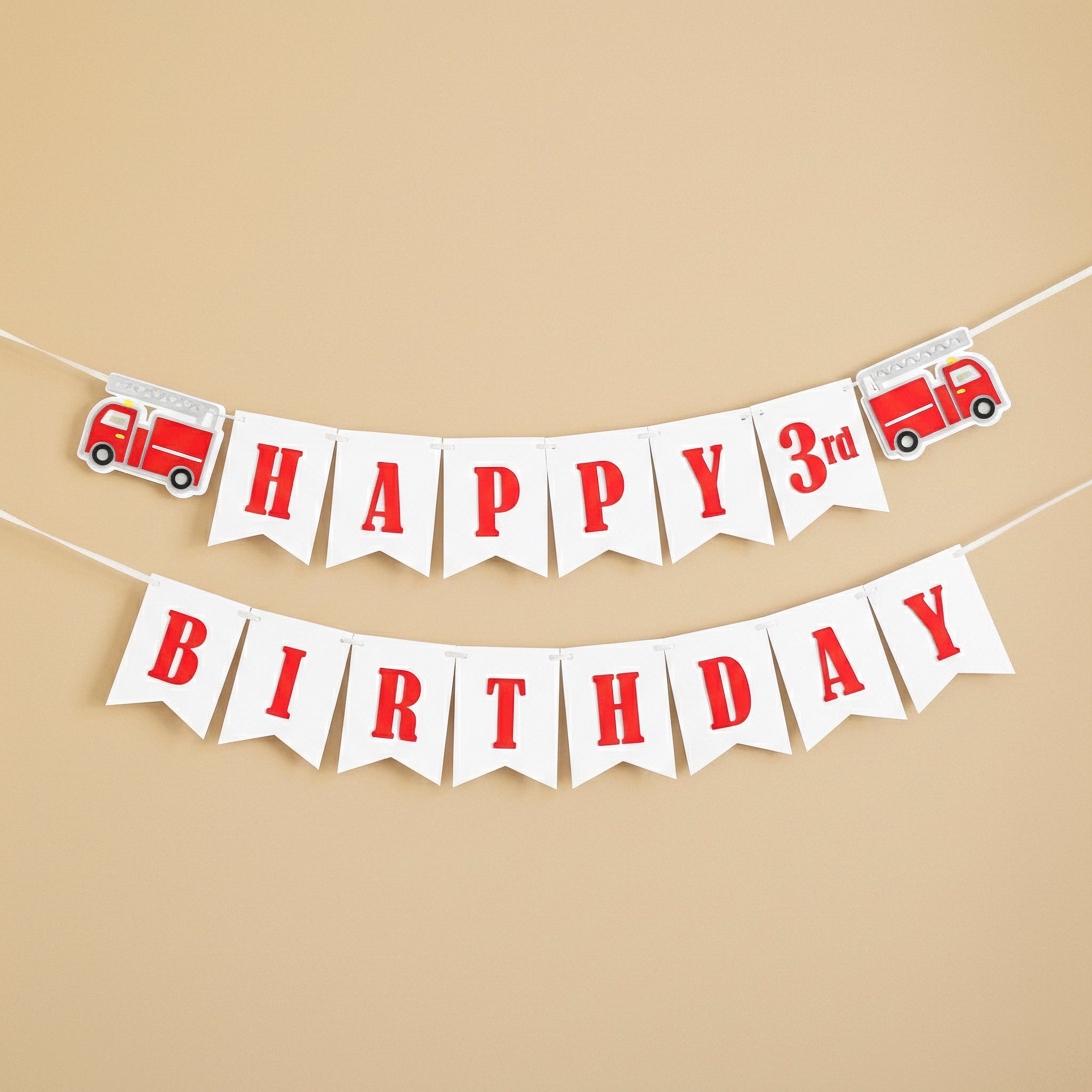 A white cardstock birthday banner with red lettering reading "HAPPY 3rd BIRTHDAY" flanked by red fire truck cutouts.