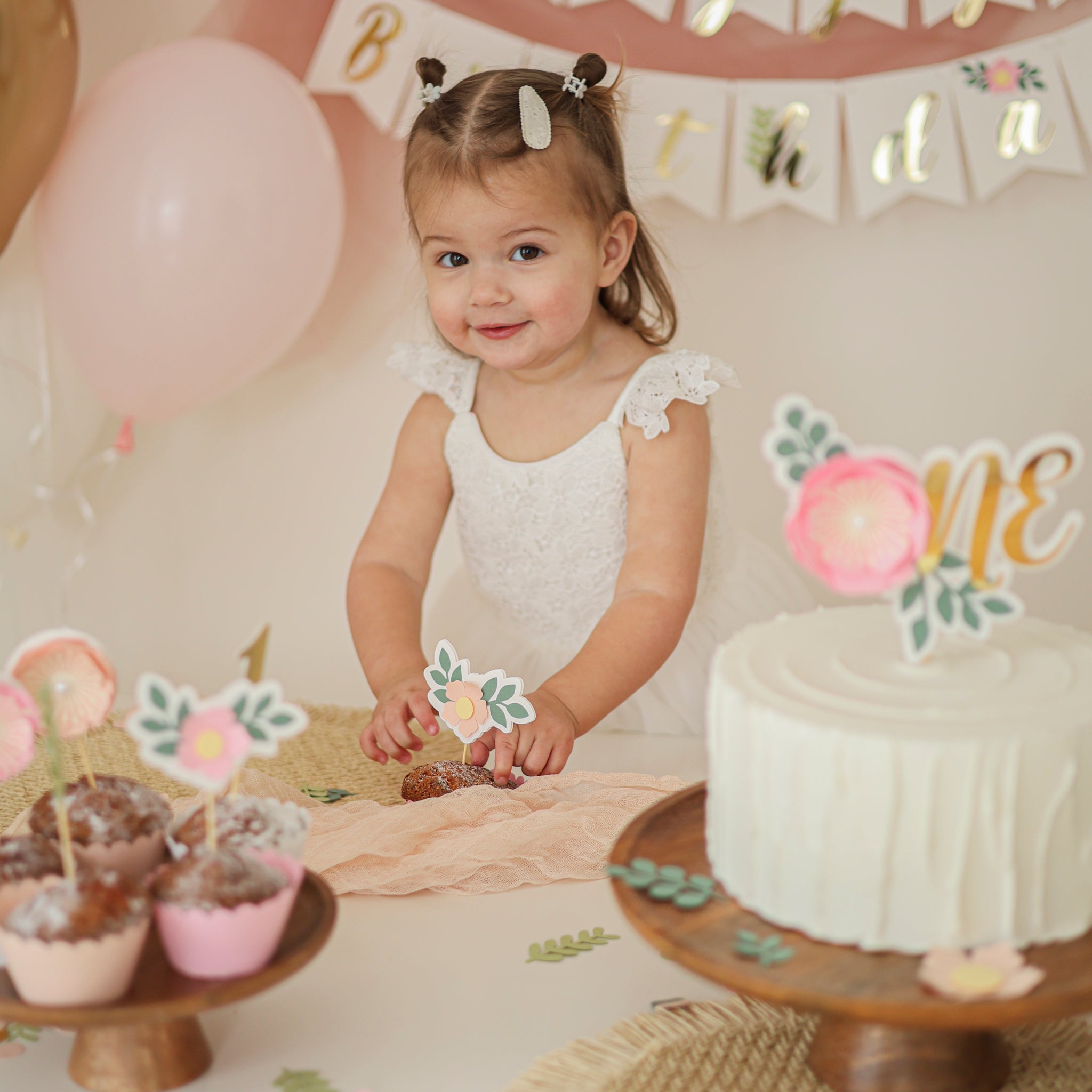 Young girl celebrating a birthday with a cake and balloons in the background