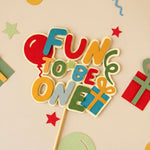 Colorful 'Fun to be One' birthday decoration on a beige background with stars and balloons.
