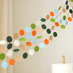 Modern dinosaur circle garland draped over a crib or shelf as neutral-colored nursery wall decor.