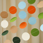 Close-up of a hand-sewn dinosaur paper circle garland in sage green, terracotta, and cream for a boho baby shower.