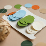 Close-up of a hand-sewn dinosaur paper circle garland in sage green, terracotta, and cream for a boho baby shower.