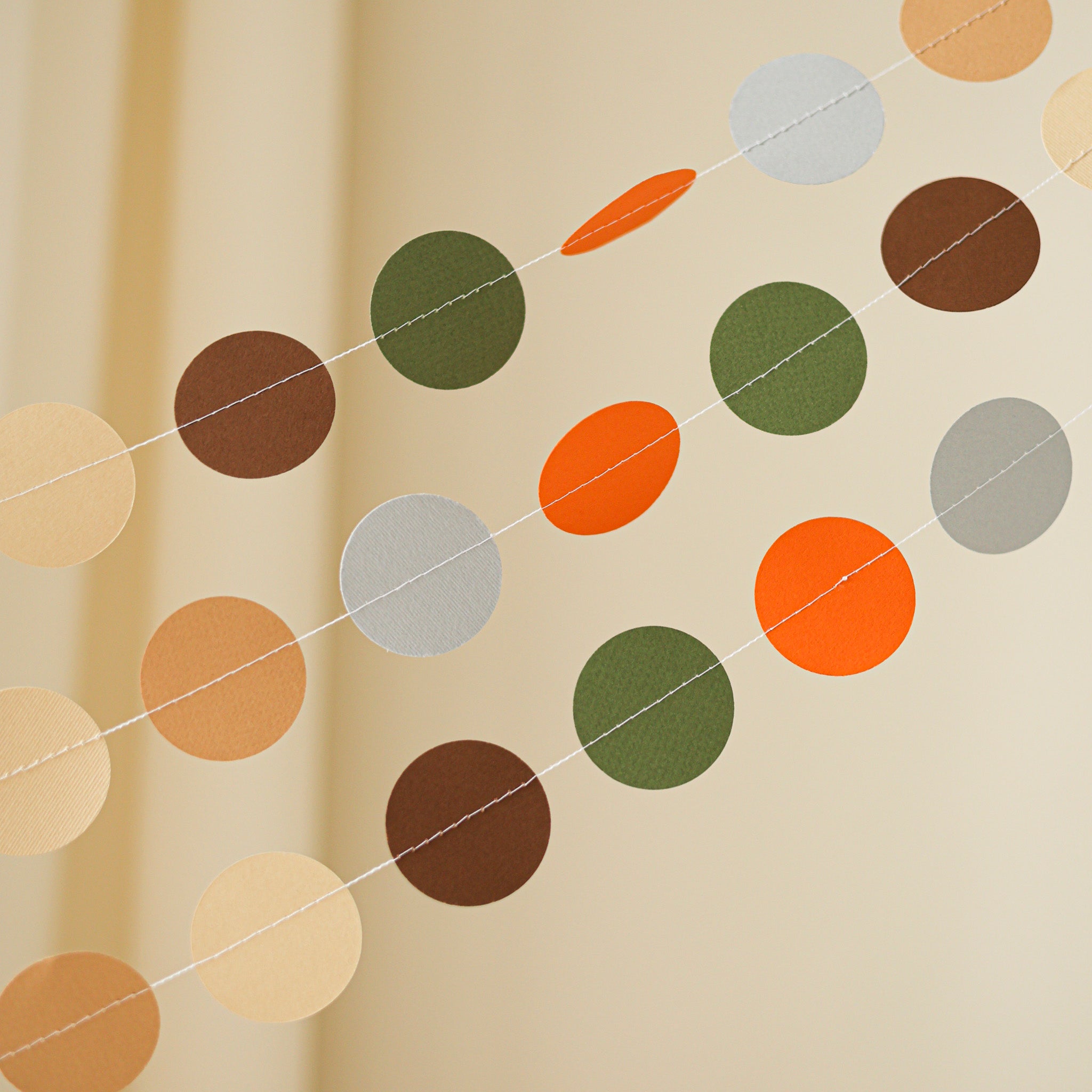 Detail of machine-stitched paper circle banner in earthy tones for rustic woodland birthday party decorations.