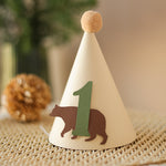 Close-up of a minimalist cardstock bear silhouette and textured sage green number one on a party hat.