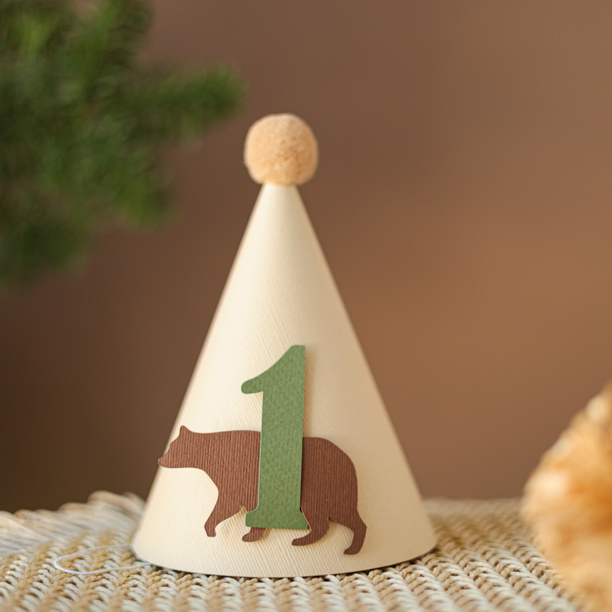 Handmade woodland bear first birthday party hat in cream with sage green number one and tan pom-pom.