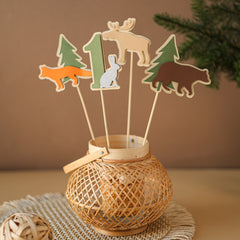 Woodland First Birthday centerpiece featuring a green number one, fox, bear, moose, and rabbit paper cutouts on wooden sticks for "Respect The Locals" table decor.
