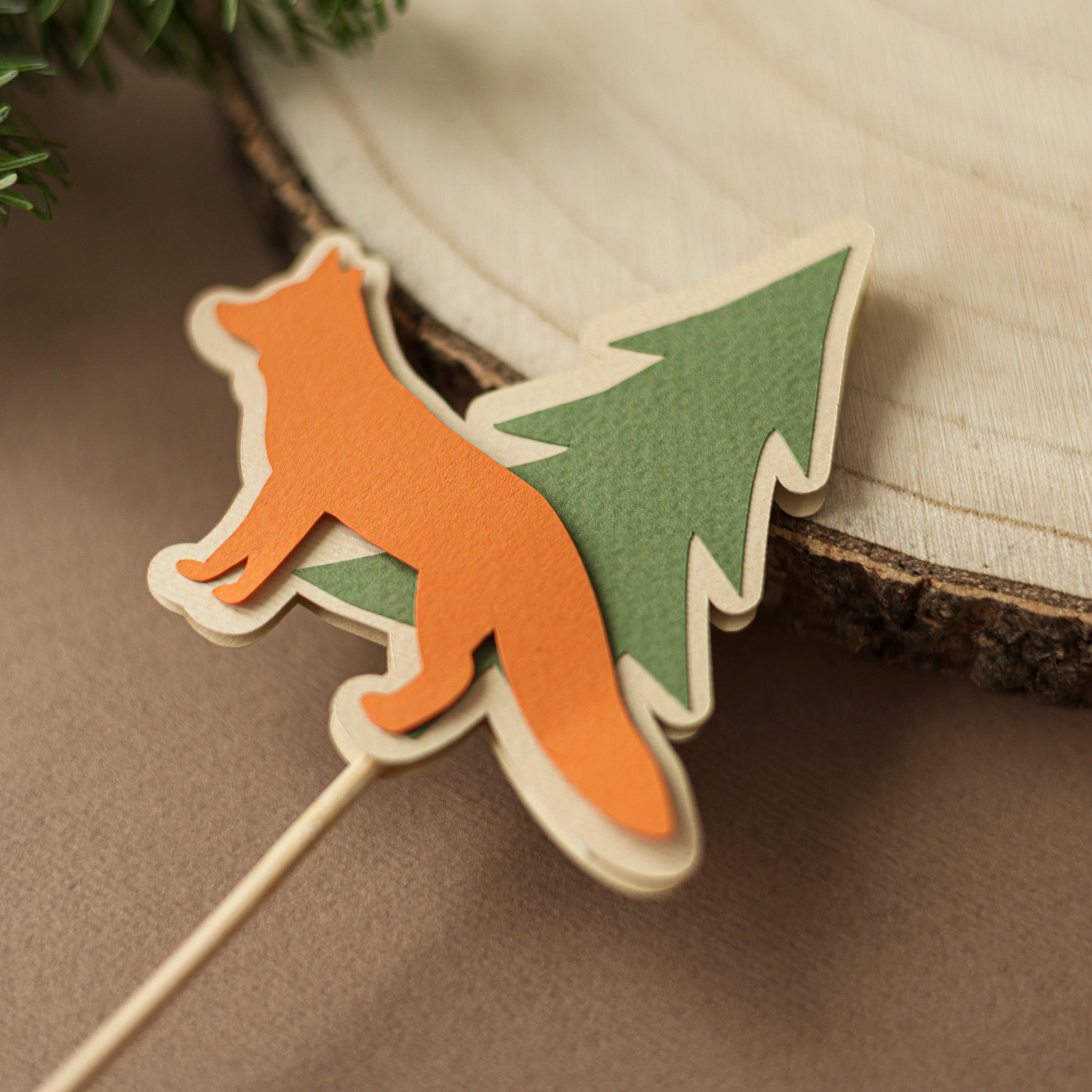 Decorative pick with fox and tree design on a wooden surface