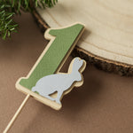 Sage green paper number one with a white rabbit cutout on a wooden dowel, woodland birthday table decor for a Wild One party.
