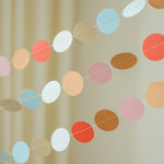Colorful polka dot garland against a beige curtain background