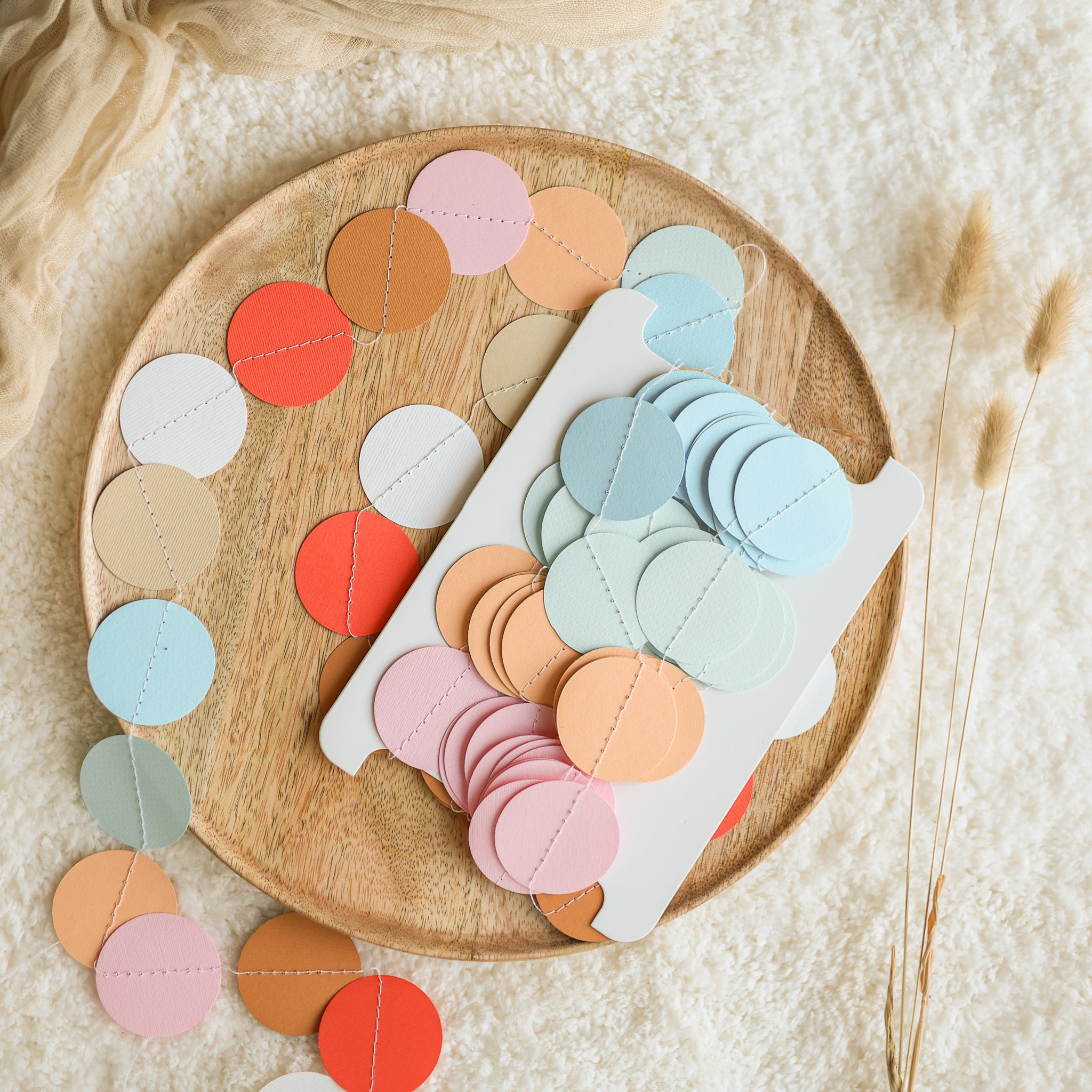 Colorful circular fabric pieces on a wooden board with a soft beige background