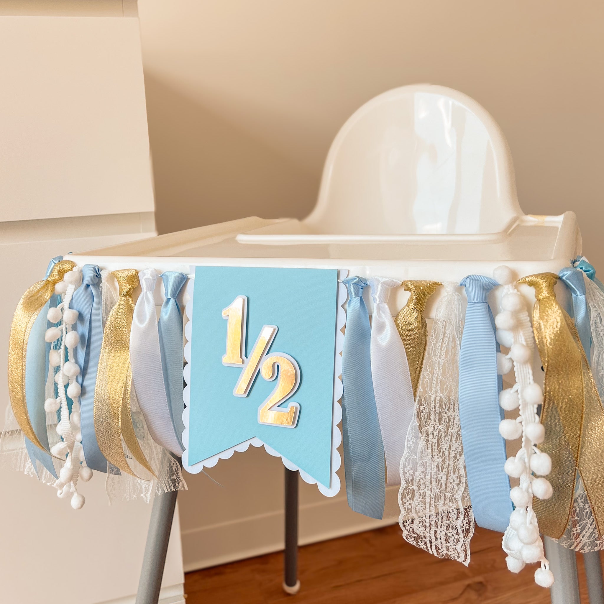 Decorative high chair with a blue and gold banner featuring the number '1 1/2'.