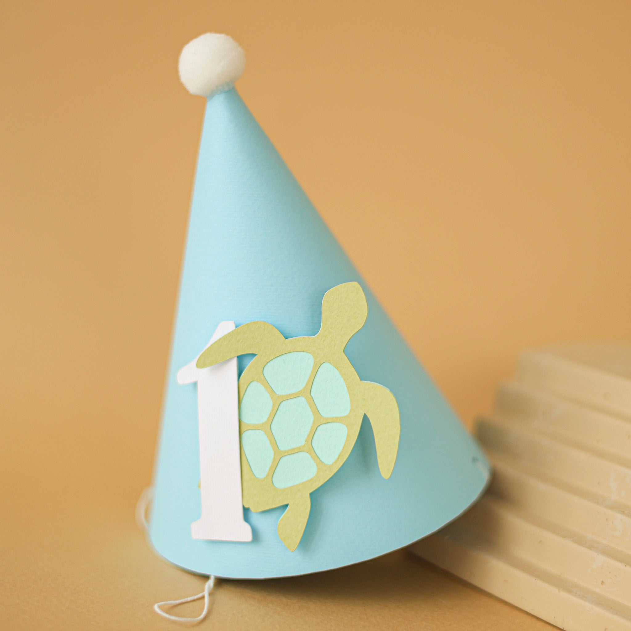 Light blue party hat with a turtle design and number '1' for baby boy 1st birthday party