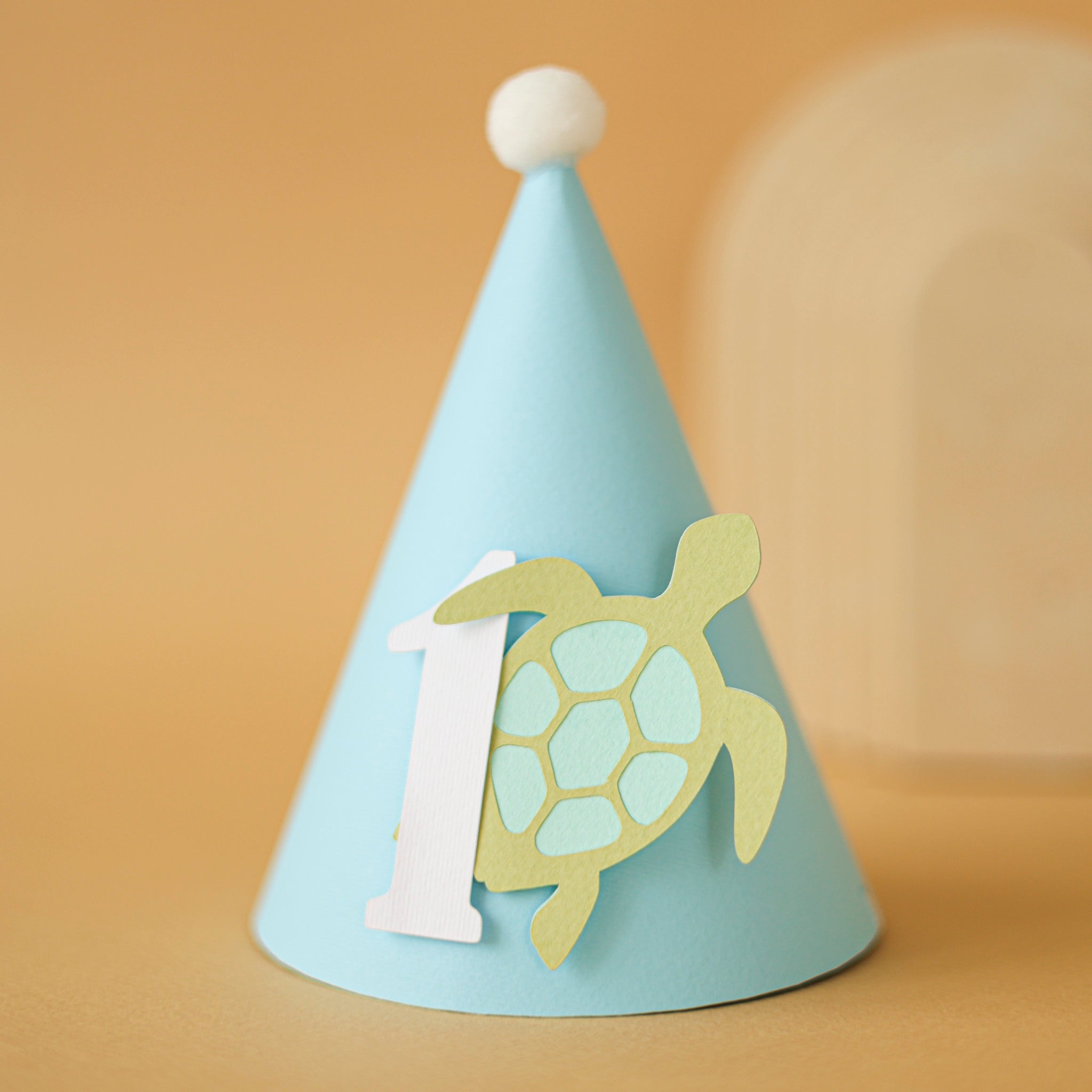 Light blue party hat with a turtle design and number '1' for baby boy ocean 1st birthday party