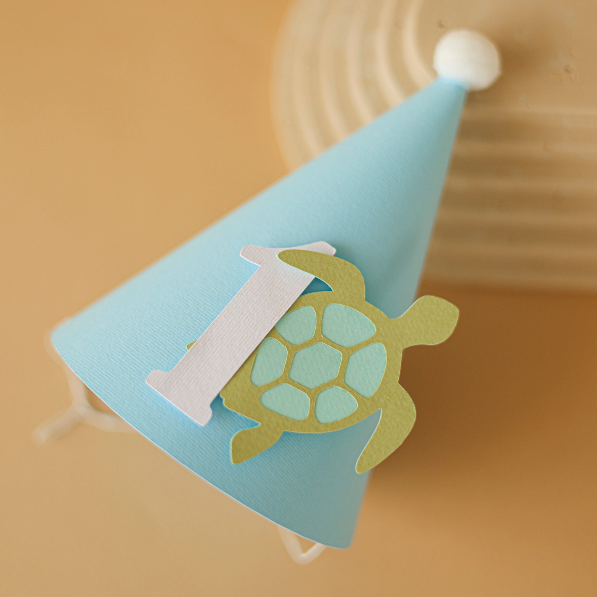 Light blue party hat with a turtle design and number '1' for baby boy ocean 1st birthday party