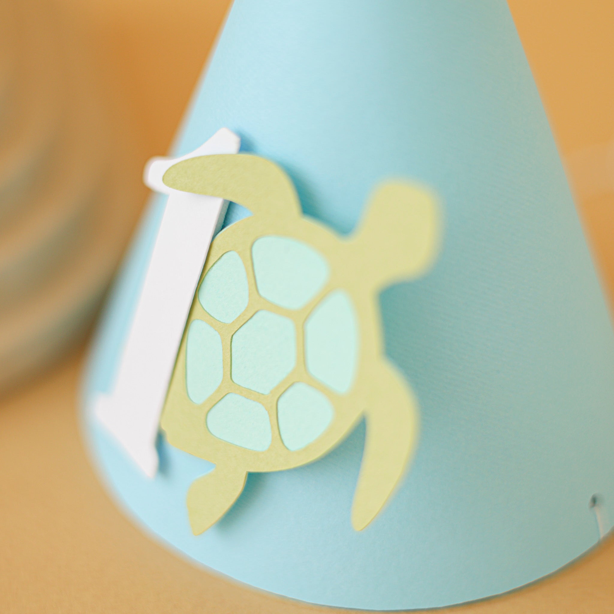 Light blue party hat with a turtle design and number '1' for baby boy ocean 1st birthday party
