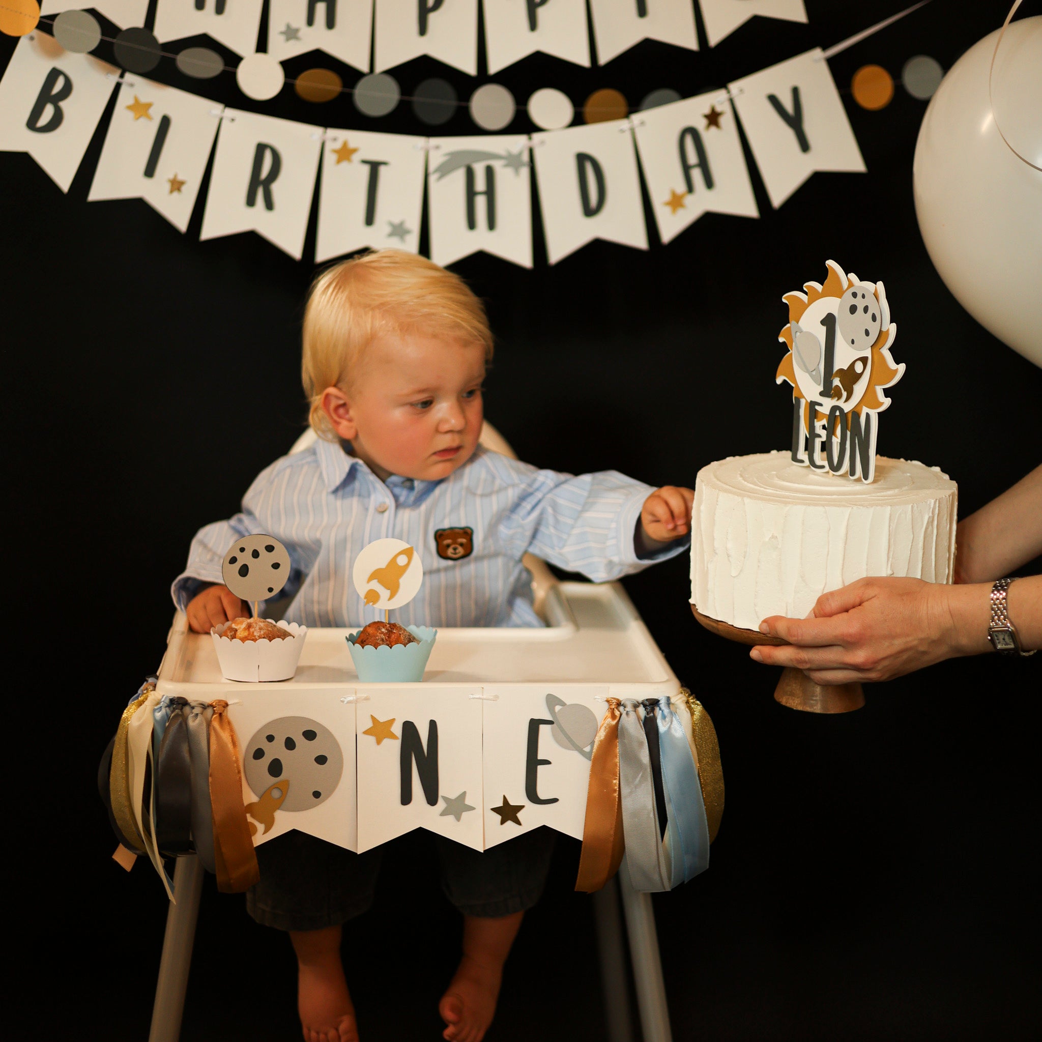 Child celebrating his first birthday with Space theme highchair banner and 1st Trip Around the Sun cake topper