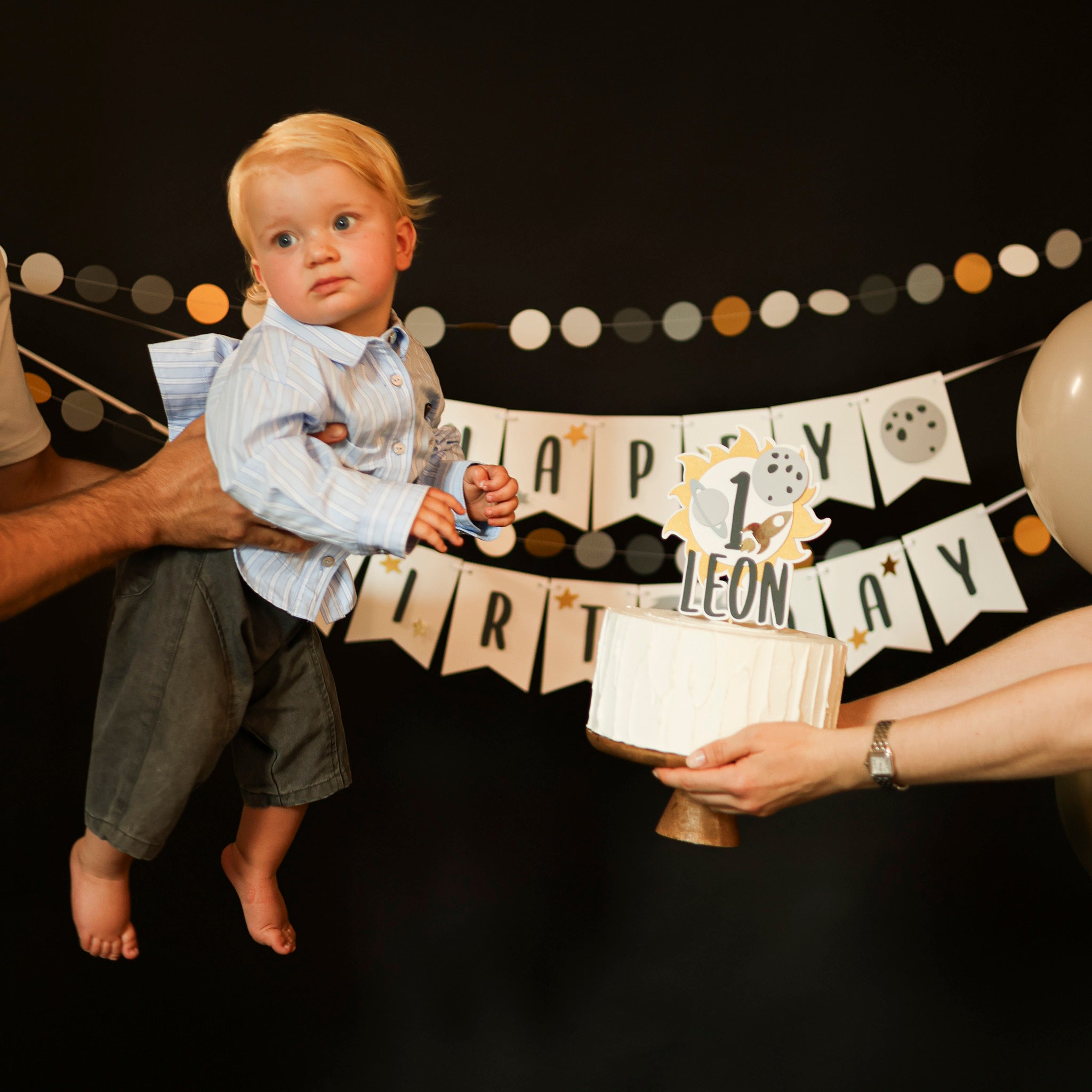 Child celebrating his first birthday with Space theme banner and 1st Trip Around the Sun cake topper