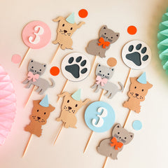 A set of cute animal party toppers for a  birthday, including cat and dog figures, paw print signs, and number circles