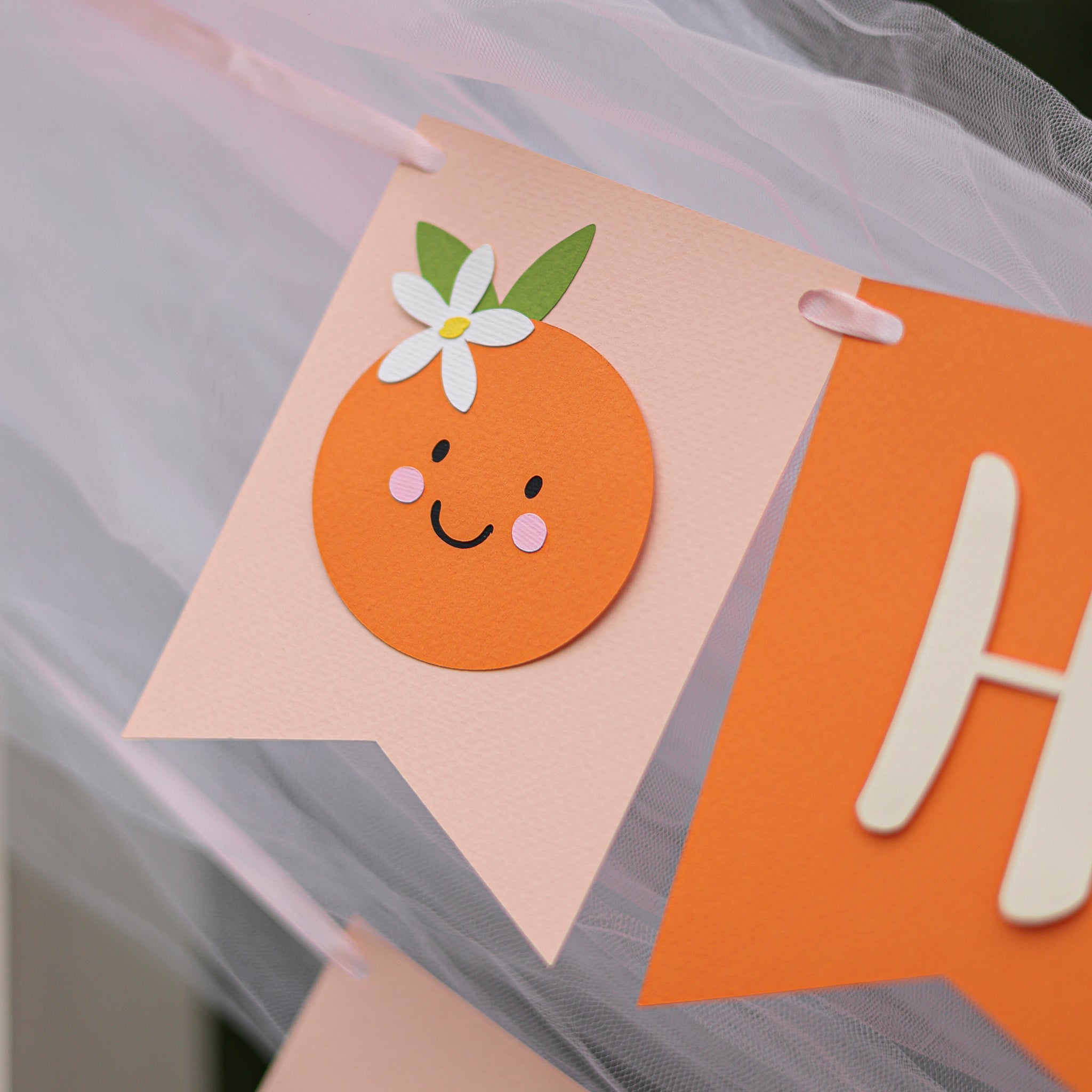 Close-up of a 'Little Cutie' themed first birthday banner. First birthday Little Cutie banner, orange citrus party decor, baby 1st birthday sign