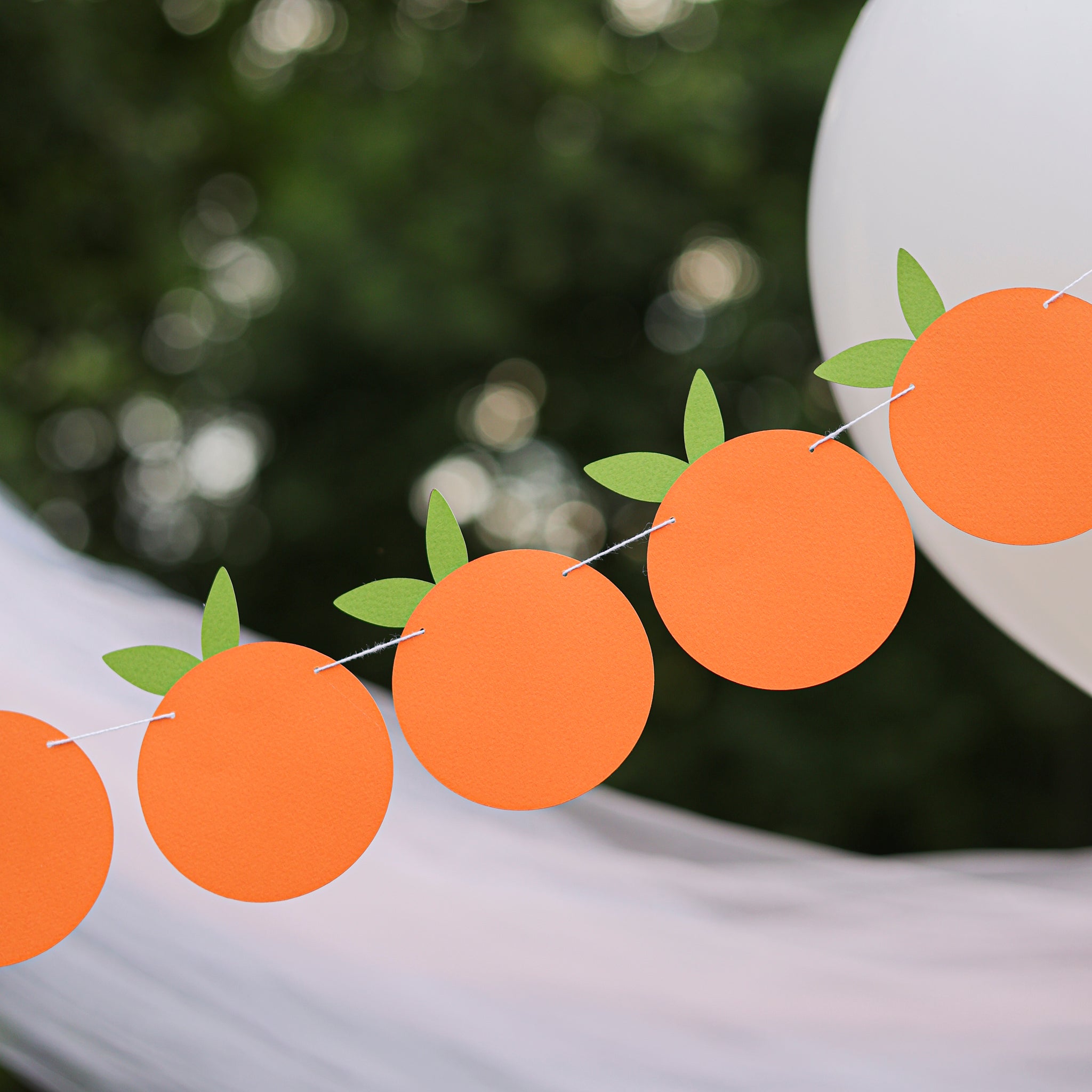 Little Cutie themed orange fruit garland for a birthday or baby shower, hanging outdoors