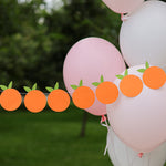 Little Cutie themed orange fruit garland for a birthday or baby shower, hanging outdoors