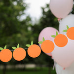 Little Cutie themed orange fruit garland for a birthday or baby shower, hanging outdoors