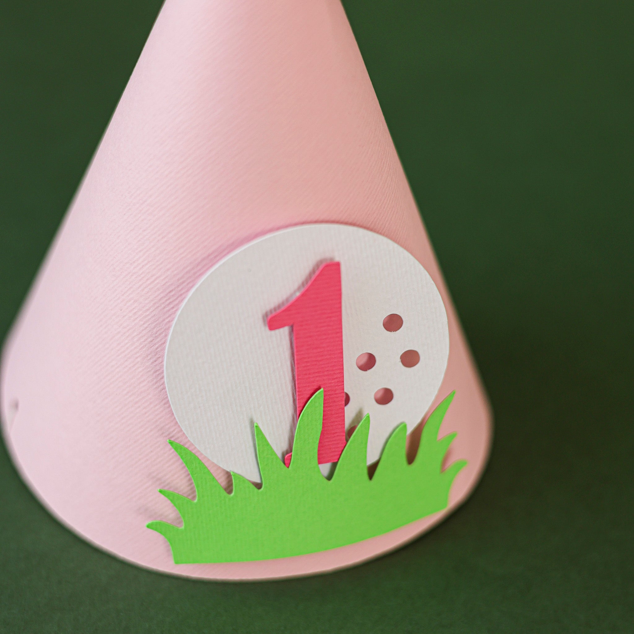 Pink party hat with a golf-themed design 