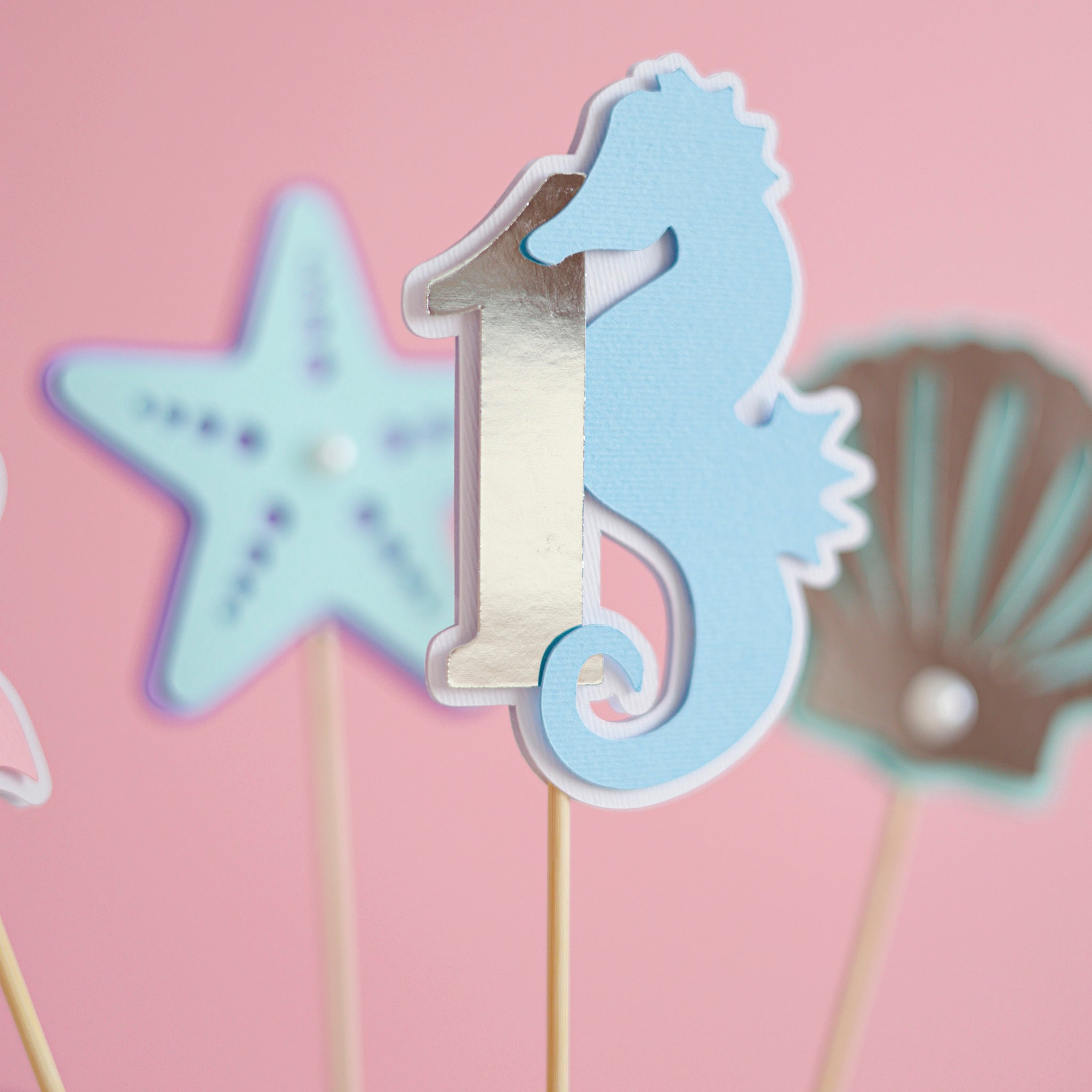 Pastel blue seahorse wrapped around a silver foil number 1 centerpiece stick for under the sea 1st birthday party