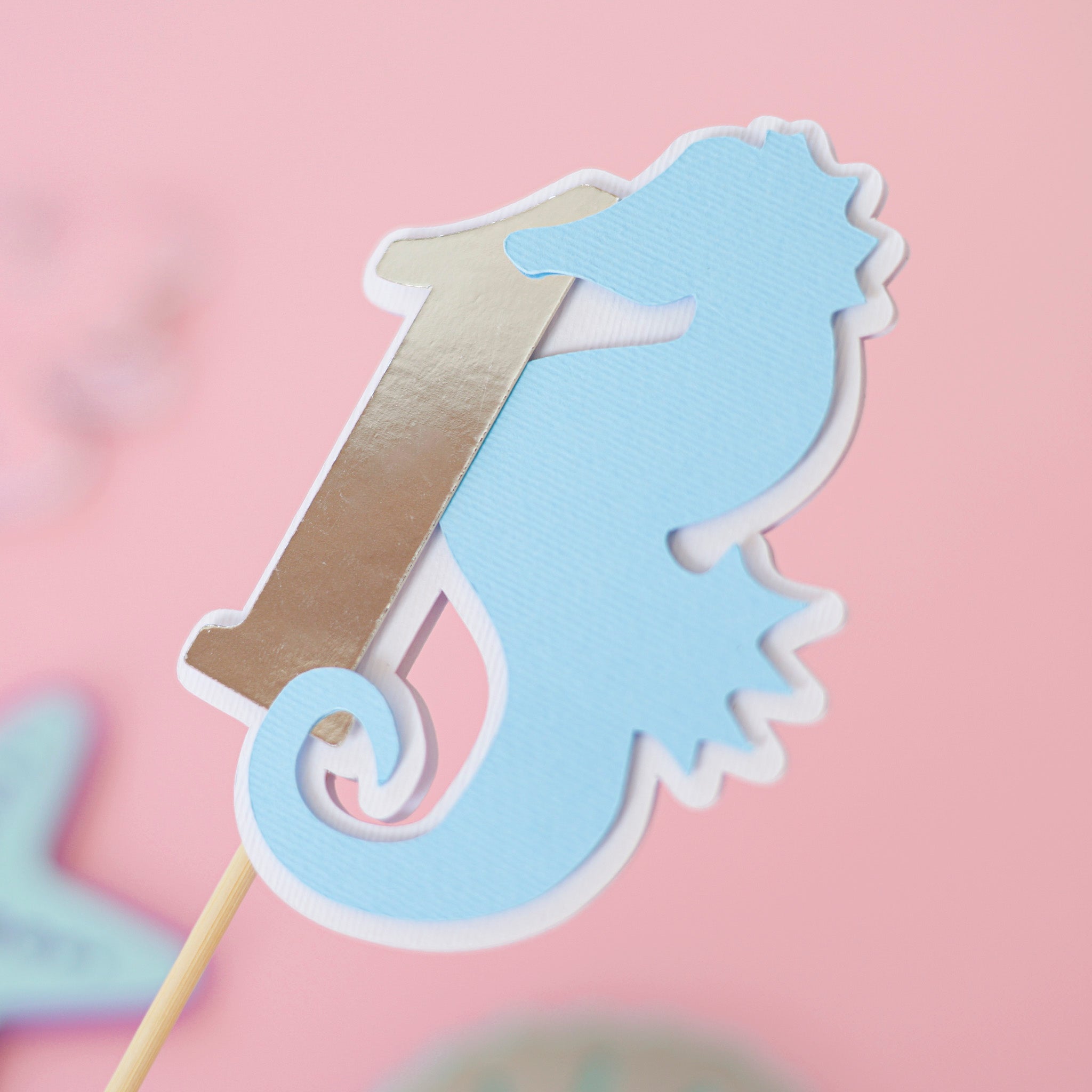 Pastel blue seahorse wrapped around a silver foil number 1 centerpiece stick for under the sea 1st birthday party