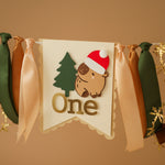 Decorative banner with a capybara wearing a Santa hat and the word 'One' 