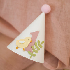 Handcrafted pastel yellow chick 1st birthday paper cone hat with dusty pink number one and light pink pom-pom