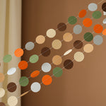 Close up of Woodland Garland with moss green, burnt orange, and brown paper circles for forest baby shower.