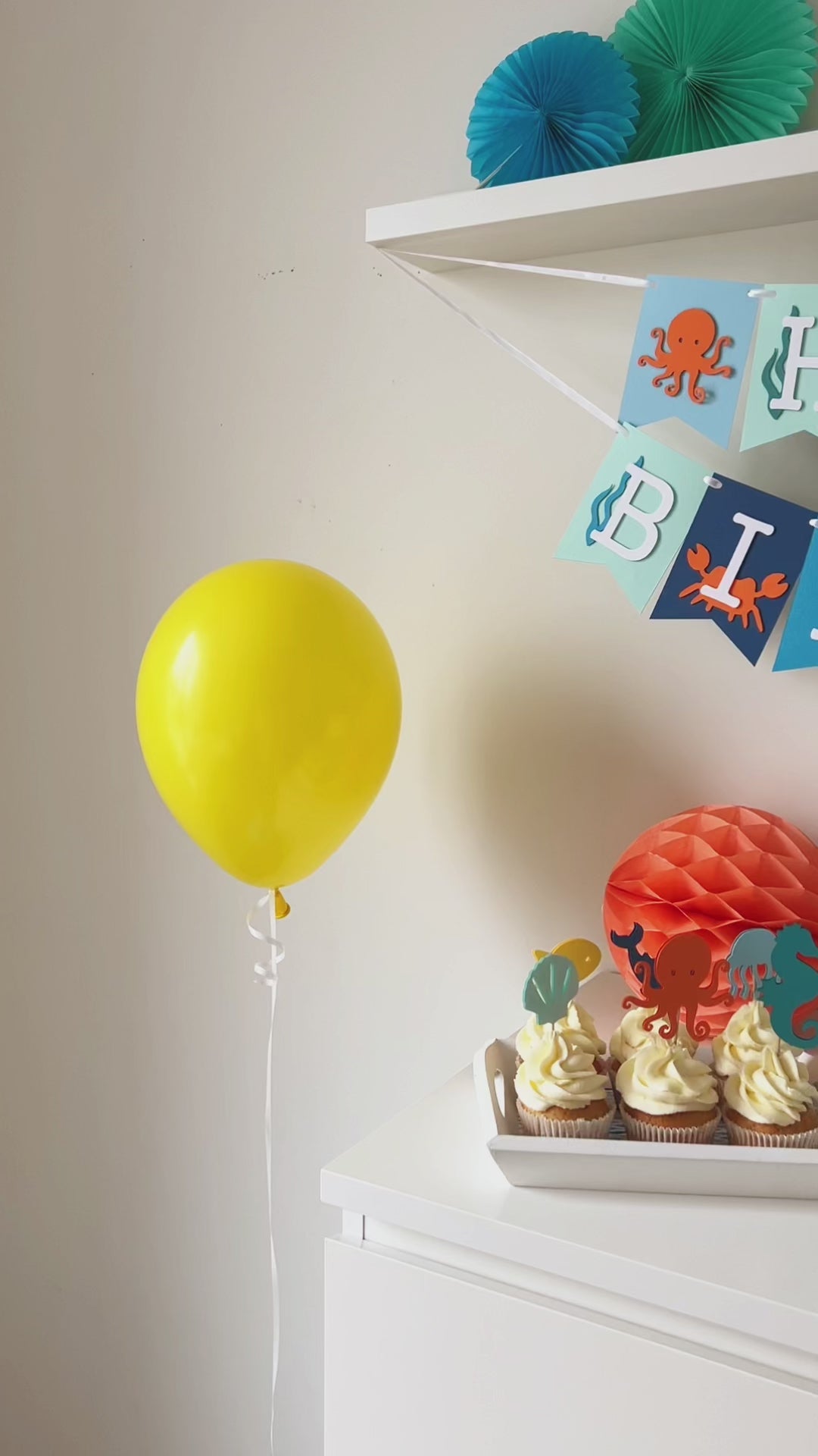 Video demonstrating the components of the 'Under the Sea Ocean Birthday Bundle' package, including close-ups of the detailed cupcake toppers (seahorse, shark), texture of the paper garland, and the design of the party hat and banners.